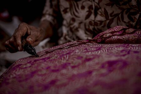 Batik, Close Up hand and canting, making Batik Tulis Indonesia. Canting is tool for drawing the texture on the fabric.の写真素材
