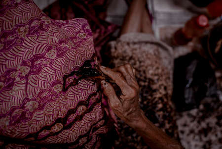 Indonesia June 18, 2020 : Batik, Close Up hand and canting, making Batik Tulis Indonesia. Canting is tool for drawing the texture on the fabric.のeditorial素材