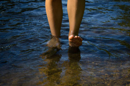 Legs of a young woman walking by the sea. Young woman's barefoot walking in the stream. Front view.の写真素材