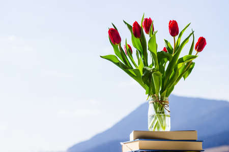 bunch of tulips in a glass vase against blue sky, colorful spring flowers on blurred background with free copy space, springtime conceptの写真素材