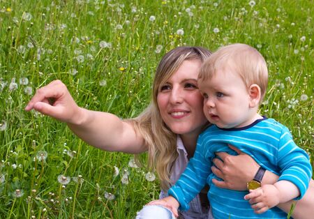 young mother with her son on the green grassの写真素材
