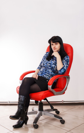 young beautiful woman sitting on a red chairの写真素材
