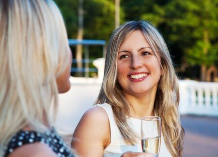 young beautiful woman in a white dress holding a glass of champagne at a partyの写真素材