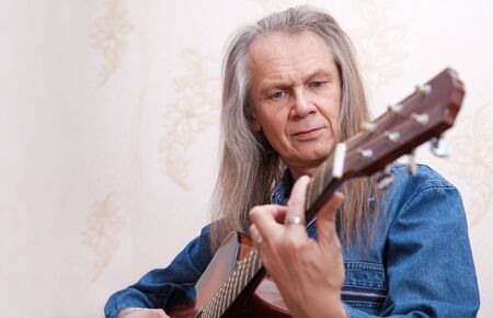 middle-aged man playing guitar at home closeupの写真素材
