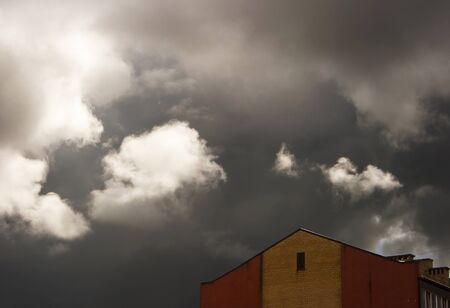 dark storm cloud over the roof of the house on spring dayの写真素材
