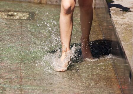 girl's feet playing in the fountain closeup on summer dayの写真素材