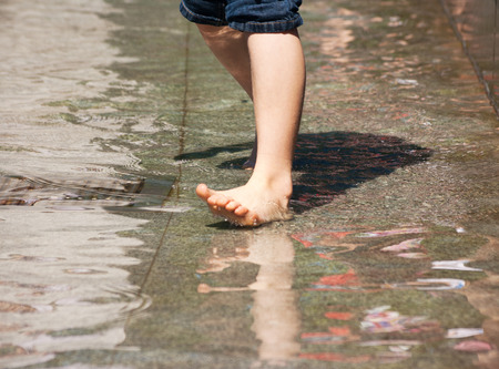 boy's feet playing the fountain closeup on summer dayの写真素材