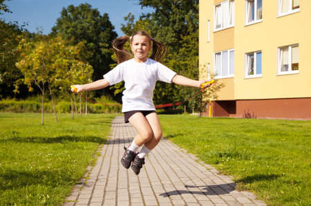little girl in white shirt and black shorts jumping rope outsideの写真素材