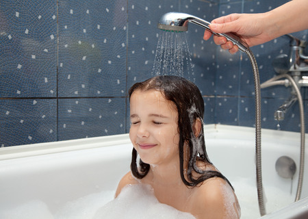 mothers's hand pours a little girl out of the shower in the bathroom closeup