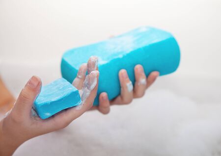 girl holding blue soap and sponge. hands closeup