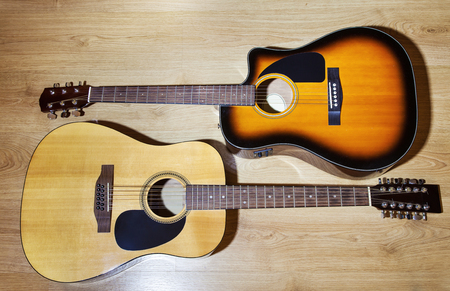 two acoustic guitars lying on wooden floor closeupの写真素材