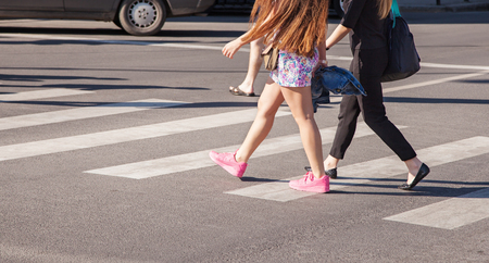 two girls pedestrians walking on a crosswalk closeupの写真素材