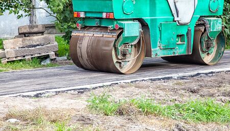 roller rolling new asphalt on the pavement outdoor on summer day closeup