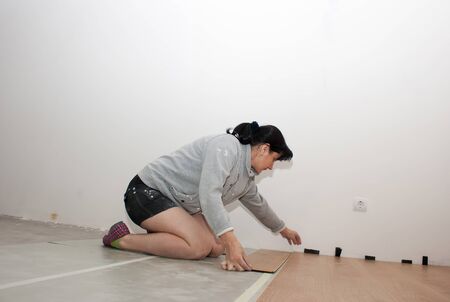 young beautiful woman puting laminate flooringの写真素材