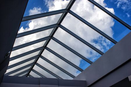 view of the cloudy sky through the glass roof on sunny summer dayの写真素材