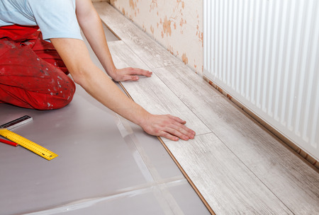 young handyman installing wooden floor in new houseの写真素材