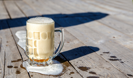 glass mug with beer on the table in the park on sunny summer dayの写真素材