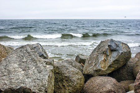 sea waves break down on a large stone on overcast summer dayの写真素材