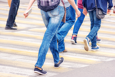pedestrians walk on a pedestrian crossing on sunny summer dayの写真素材