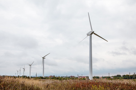 modern windmills in the field on gloomy cloudy autumn day