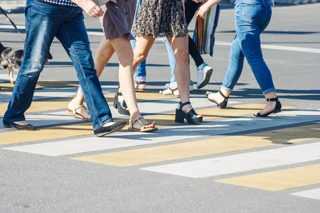 pedestrians crossing the road at a pedestrian crossing on summer sunny dayの写真素材