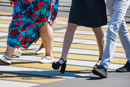 pedestrians crossing the road at a pedestrian crossing on summer sunny dayの写真素材