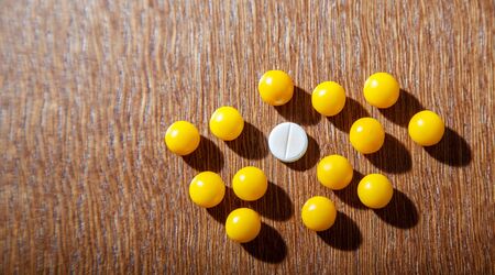 one white pill among many yellow pills on the table. concept i am different from othersの写真素材