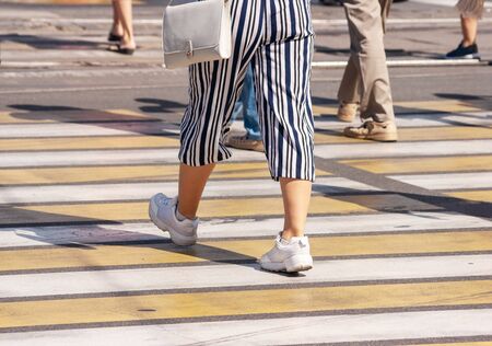 pedestrians crossing the road at a crosswalk in the city on summer day