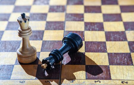 defeated black king lying at the feet of the white king on the chessboard closeup