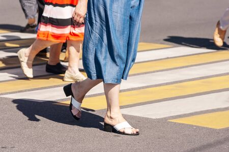 pedestrians crossing the road at a crosswalk in the city on summer day. legs closeupの写真素材