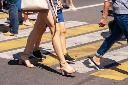 people crossing the street at pedestrian crossing on sunny summer dayの写真素材