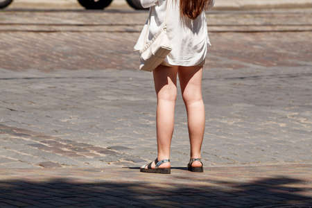 young woman waiting for a traffic signal at a crosswalk on sunny summer dayの写真素材