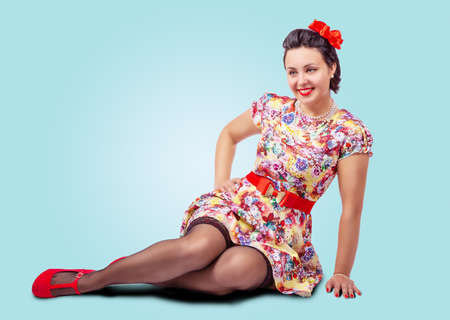 young beautiful woman posing while sitting on the floor in studio. pinup styleの写真素材