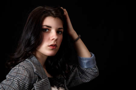portrait of a young beautiful brunette girl in business suit in studio on black backgroundの写真素材