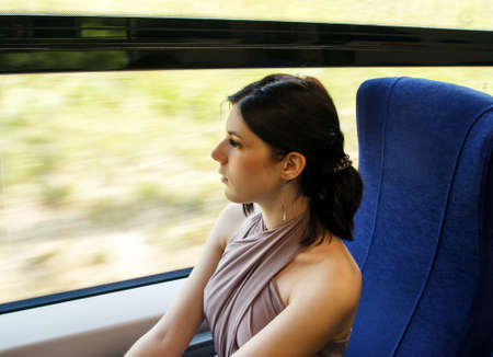 young brunette woman sitting by the window in the train. portrait closeup