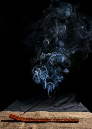 indian incense stick with smoke on black background indoor closeupの写真素材