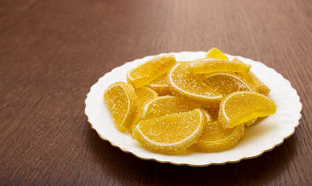 marmalade lemon slices on a white plate on a wooden table indoor closeupの写真素材