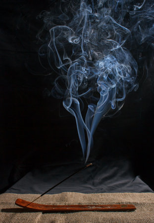 indian incense stick with smoke on black background indoor closeupの写真素材