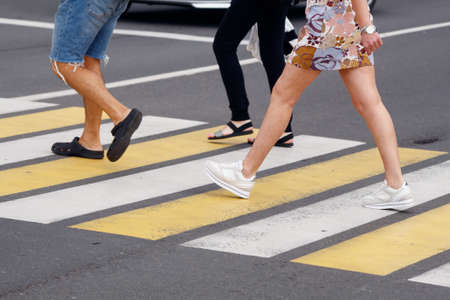 people crossing the road at a pedestrian crossing. leg closeup. outdoor on sunny summer dayの写真素材