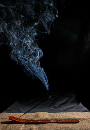 indian incense stick with smoke on black background indoor closeupの写真素材