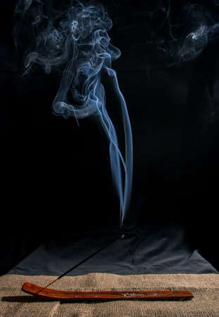 indian incense stick with smoke on black background indoor closeup