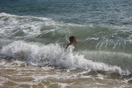 A brave boy against the rage of the Mediterranean sea. Overwhelmed,overturned, crashed  by the big wave.の写真素材