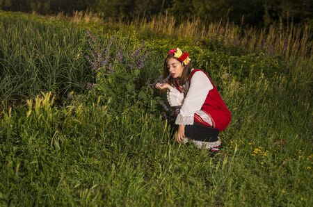Beautiful young girl dressed in a traditional Bulgarian folklore costume in the mountain on sunset