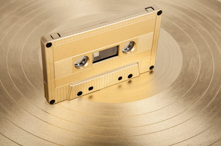Vintage audio cassette tape on golden vinyl record. Retro music concept.の写真素材
