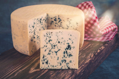 Delicious blue cheese on wooden board, close-up. toned imageの写真素材