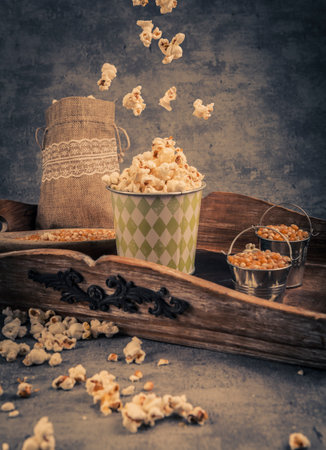 Popcorn in a paper cup and bucket on a wooden tray. Toned.の写真素材