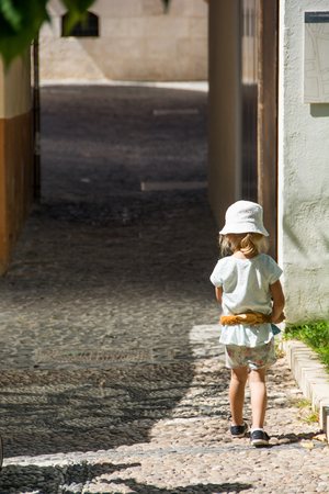 Kid walking alone, empty narrow streetの写真素材