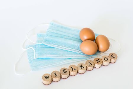 Eggs lying on face protection masks, wielkanoc means easter in polish