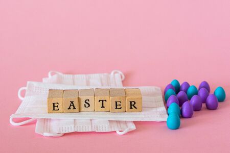 Plastic eggs on pink background, wooden letters saying easter