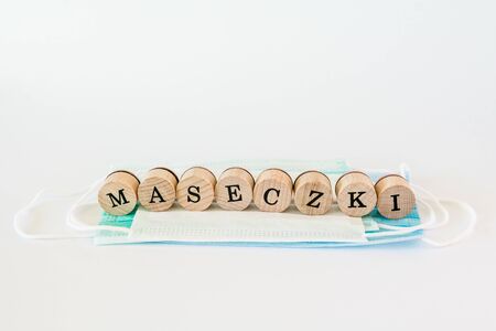 Words written with wooden blocks with black letters laying on protective surgical masks "Maseczki" means "masks" in polish.の写真素材